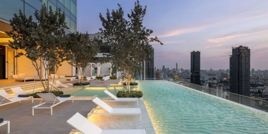 A serene rooftop pool at Eastin Grand Hotel Phayathai, bordered by trees, providing a relaxing environment for visitors.